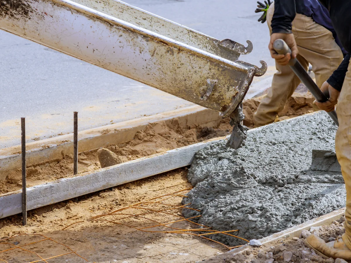 A concrete chute discharging wet mix into a formed and staked slab